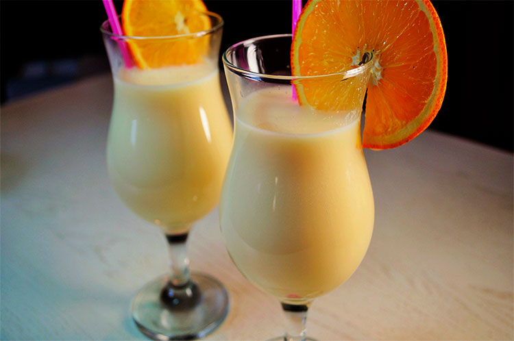 банановый молочный коктейль в бокале с долькой апельсина